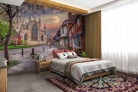 The color palette includes warm tones for the buildings, grays for the cobblestones, and dramatic hues for the sky, with the moon as a focal point.
