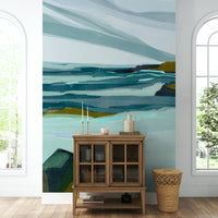 The mural is installed in a calm living room behind a simple, light-colored sofa.

