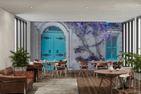 The mural shows a peaceful street scene with a blue door and purple bougainvillea.

