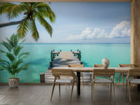 A wooden pier extends out into calm, clear turquoise water.
