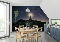 Starry night wallpaper with a glowing lighthouse acting as a celestial guide.