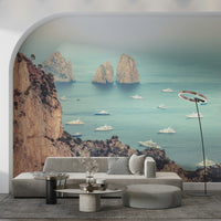 The wallpaper presents an elegant view of Faraglioni cliffs overlooking shimmering blue water and distant boats.