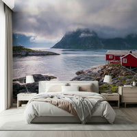 Atmospheric fjord wallpaper mural with low clouds, still water, and a bright red shoreline cabin.
