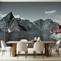 Coastal mountain mural with massive fjord cliffs and a vibrant red cabin at the water's edge.