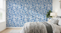 Indigo roses cluster along thorned stems in this Wild Blue and White wallpaper.