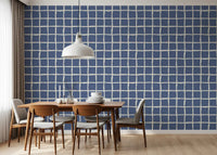Stamped blocks in dusty blue float between cream lanes of this wavy grid wallpaper