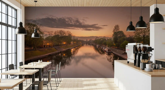 Wandmuurschildering met spiegelend kanaalwater bij zonsondergang