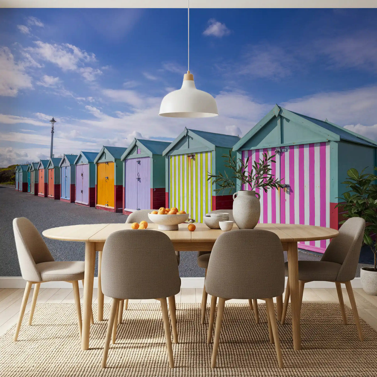 Beach wallpaper behind a round oak dining table with taupe chairs and a jute rug GD13132