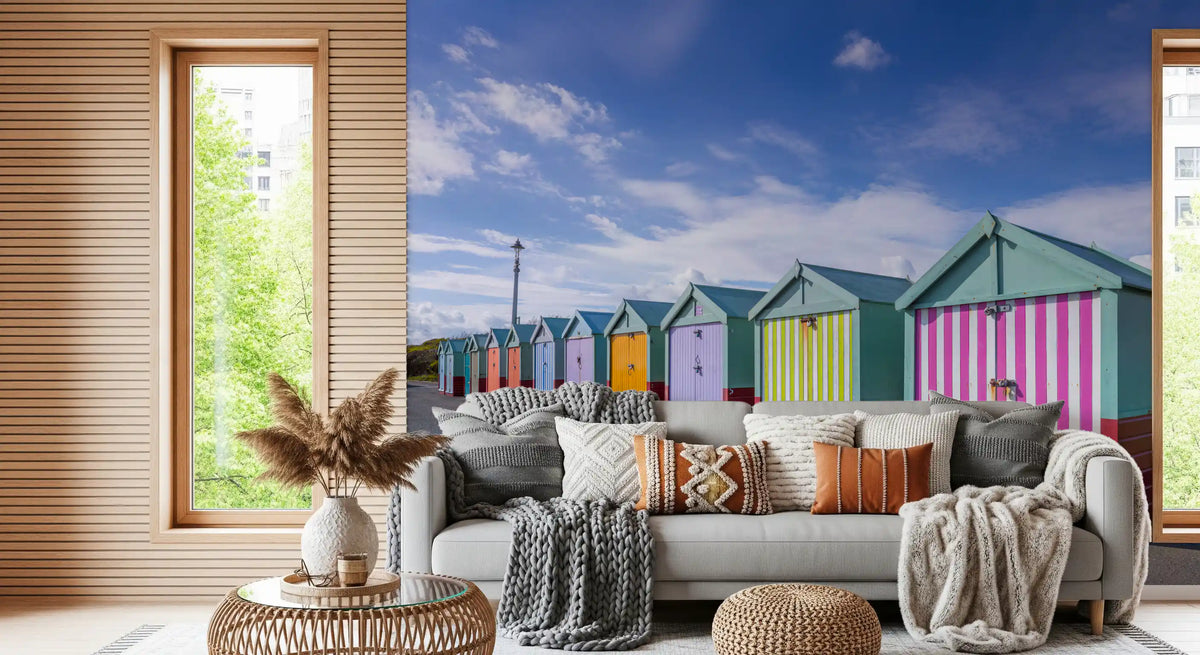 Striped beach hut mural behind a gray sofa with knit throws and a pampas vase GD13132