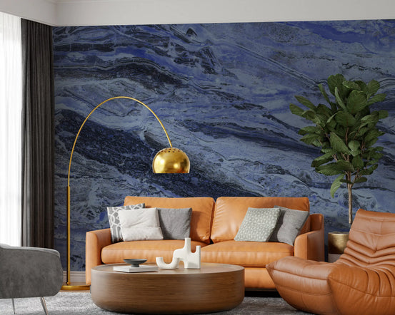 Blue marble wallpaper behind a tan leather sofa, a gold arc lamp and a fiddle leaf fig GD13994