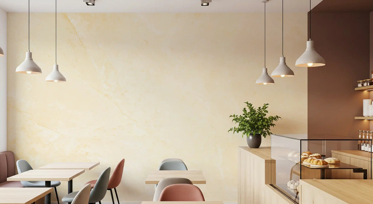 Cafe with white pendant lights, small tables and pastry counter on a creamy stone wall GD14189