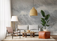 Gray loveseat, leather sling chair and cognac pouf on a cloudy marble wall mural GD14203