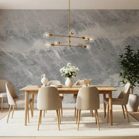 Dining room with an oak table and brass chandelier on a gray and cream marble wall GD14203