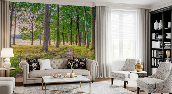Gray tufted sofa, patterned armchairs and black bookcase in front of forest wallpaper GD14219