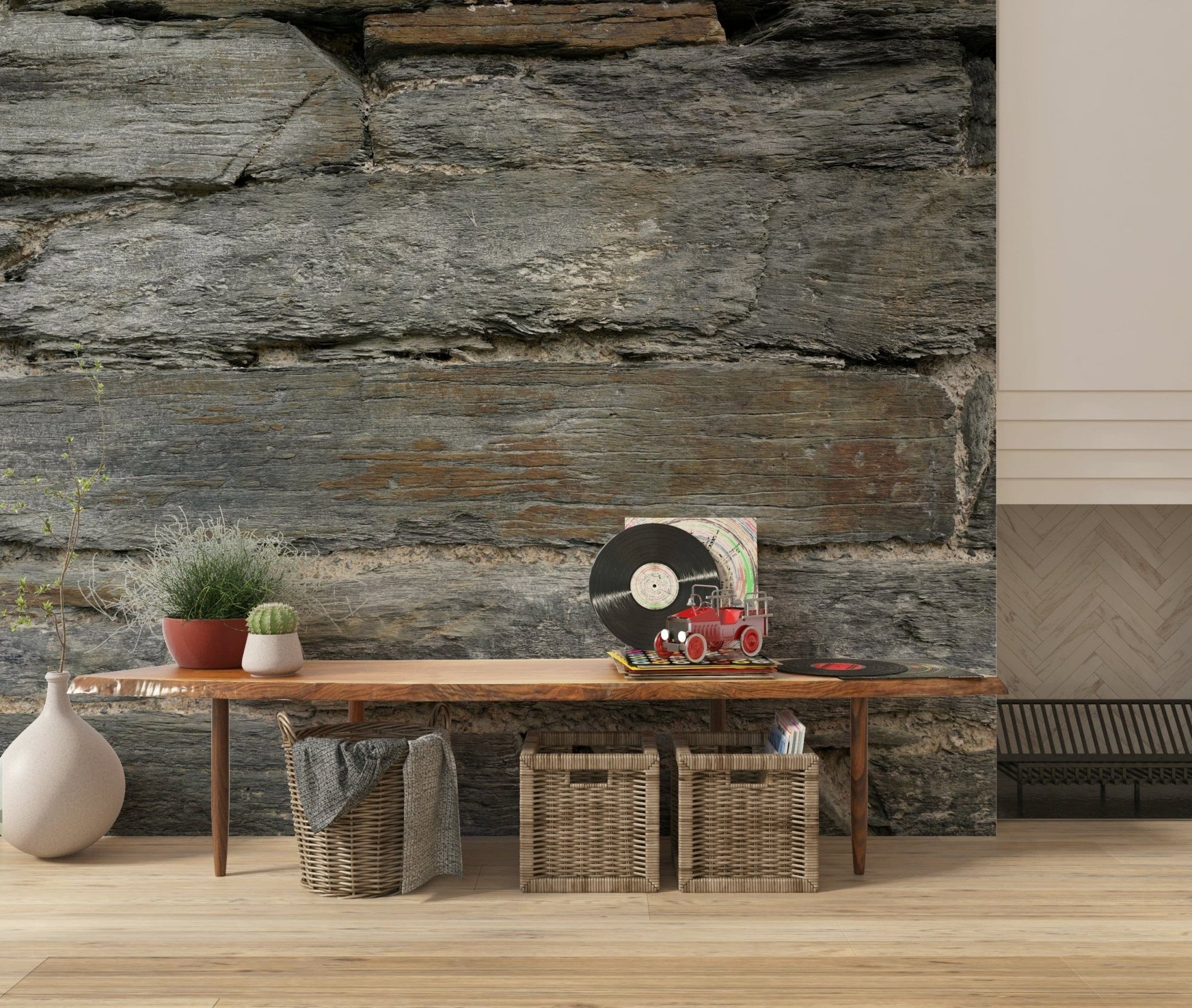 Aged Stone wallpaper mural in layered grey-brown stone behind a wood bench with a vinyl record and baskets
