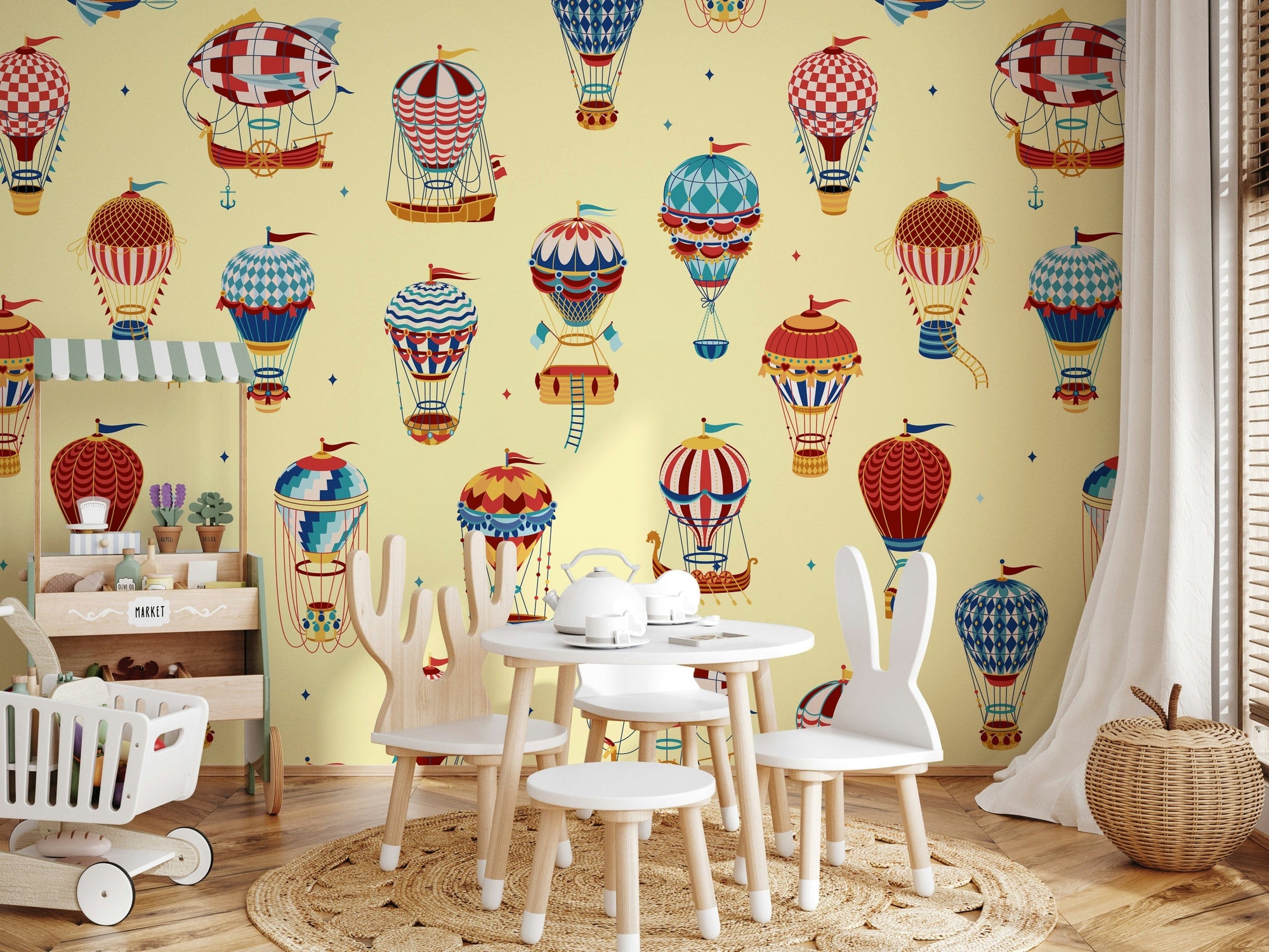 Sky High Balloon Parade wallpaper mural of balloons on yellow in a playroom with a wood market stall and bunny-ear chairs