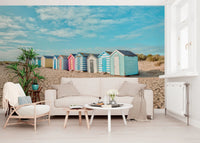 Striped wooden beach hut wall mural in a sunny coastal scene.