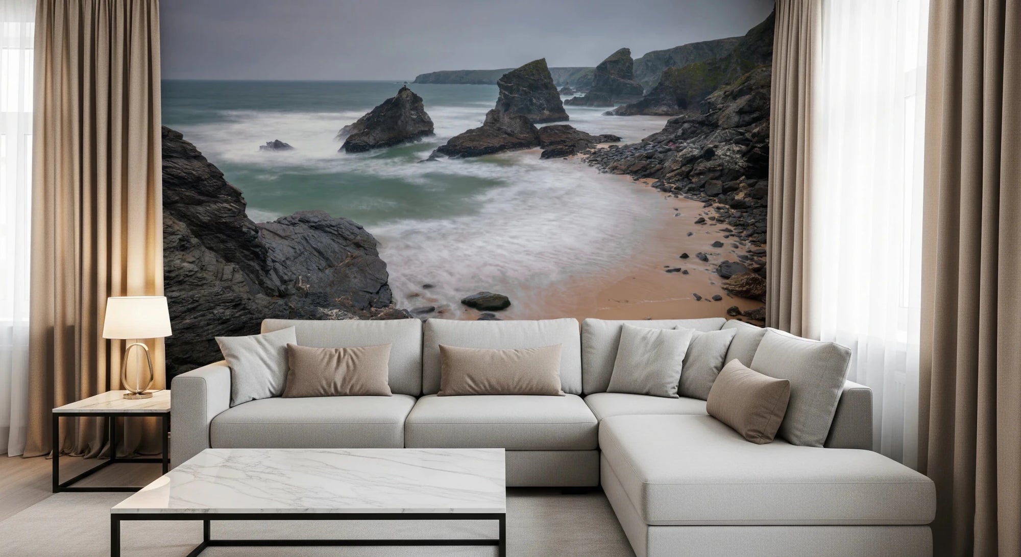 Bedruthan Steps Beach Cornwall wall mural of rocky sea stacks and surf behind a cream sectional sofa in a living room