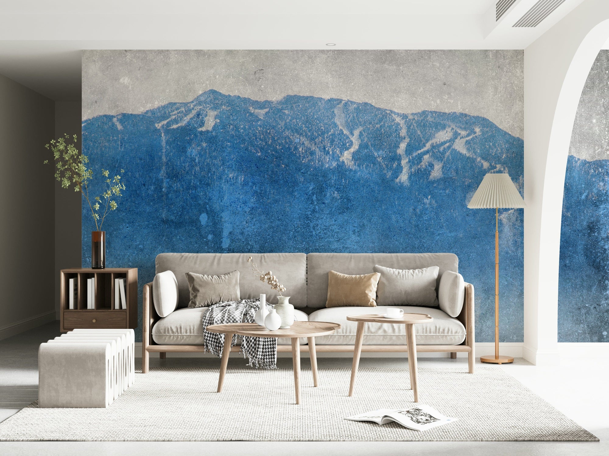 Blue Mountain Vista wallpaper mural of a blue mountain range behind a grey sofa and wood tables in a living room