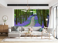 Nature wallpaper with tall forest trees and a carpet of purple-blue bluebells along a peaceful path.