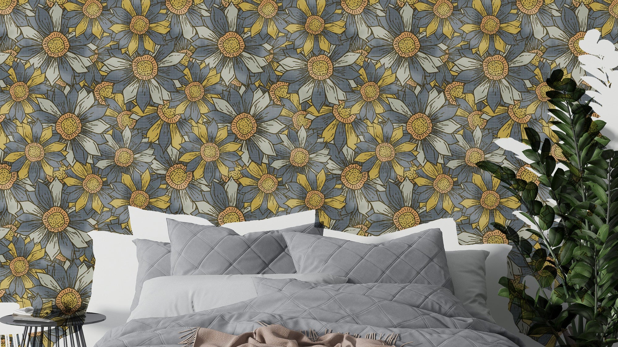 Boho Maximalist Flowers Golden and Gray wallpaper behind a gray bed and leafy plant in a bedroom