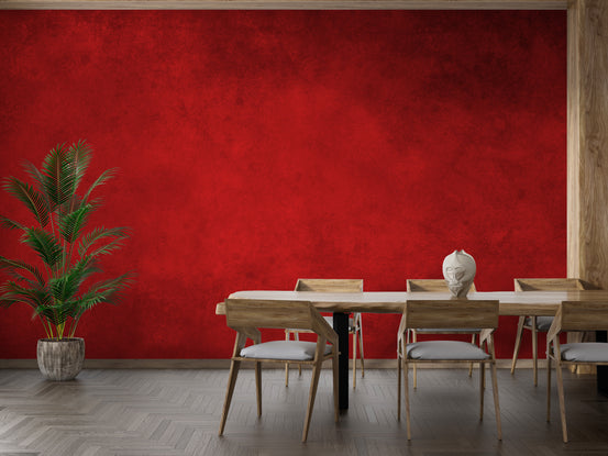 Bright Red Concrete Pattern wallpaper mural on a dining room wall with a wooden table, chairs and potted palm