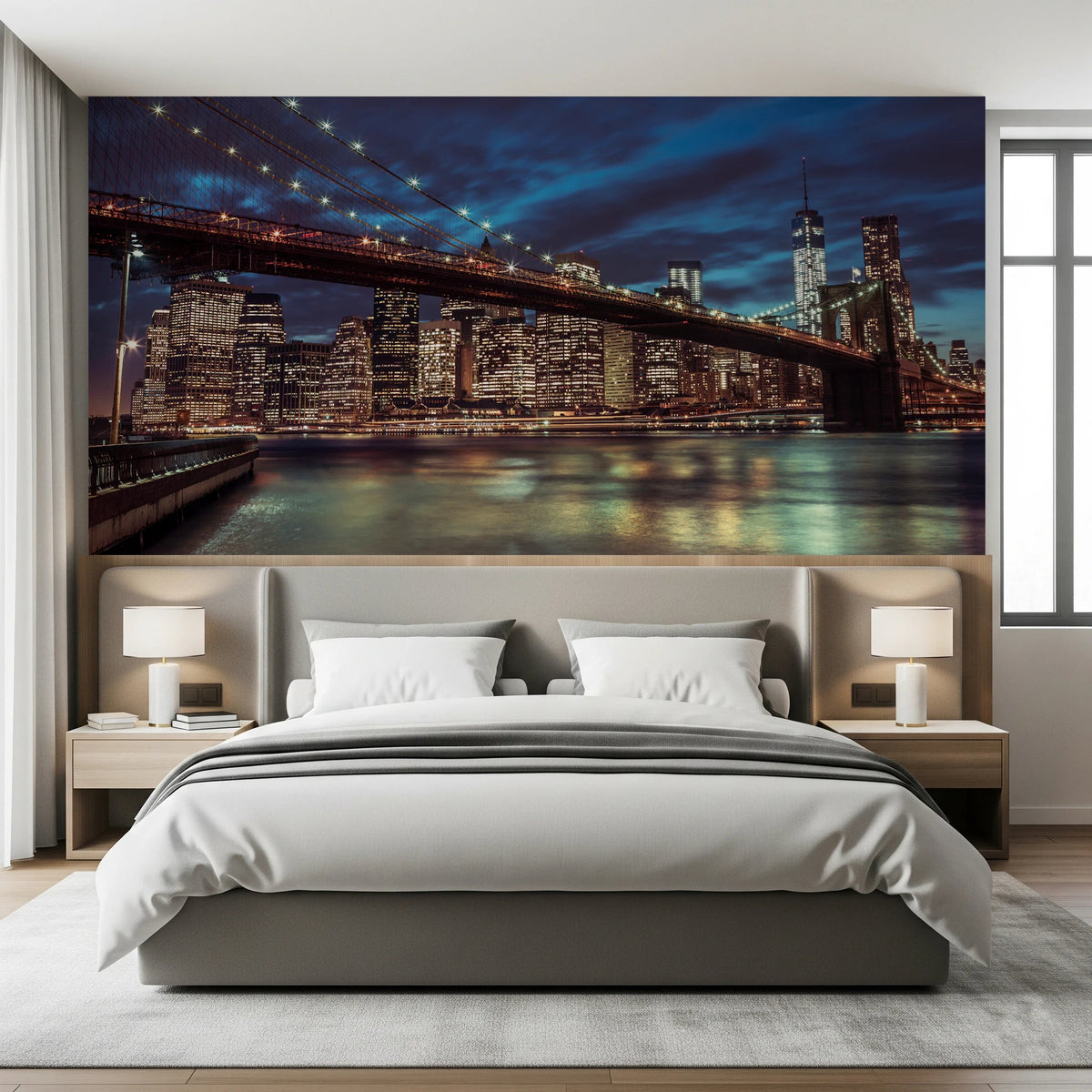 Brooklyn Bridge at Dusk mural with lit Manhattan skyline behind a gray upholstered bed and twin white lamps