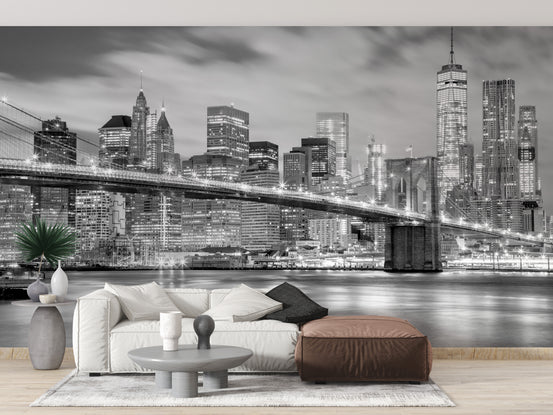 Brooklyn Bridge wallpaper mural with black-and-white night skyline behind a white sofa and brown leather ottoman in a living room