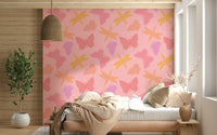 Whimsical wallpaper mural with stylized butterflies and dragonflies in shades of yellow, coral, and lavender.
