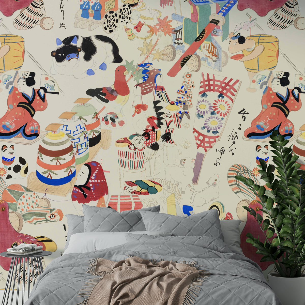 Chihiro wallpaper mural with vintage Japanese folk figures behind a gray bed and fern in a calm bedroom