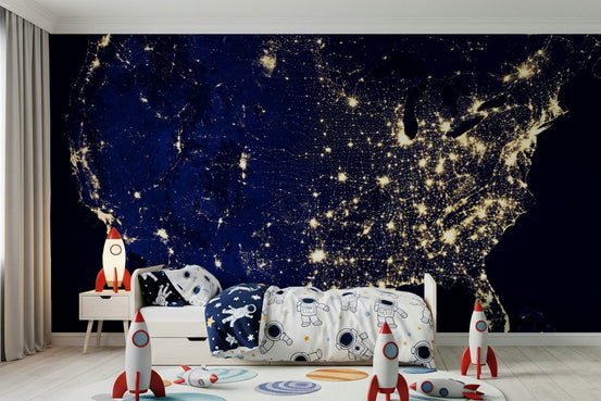 City Lights USA wallpaper mural of the glowing night-time United States behind a white kids bed with rocket toys