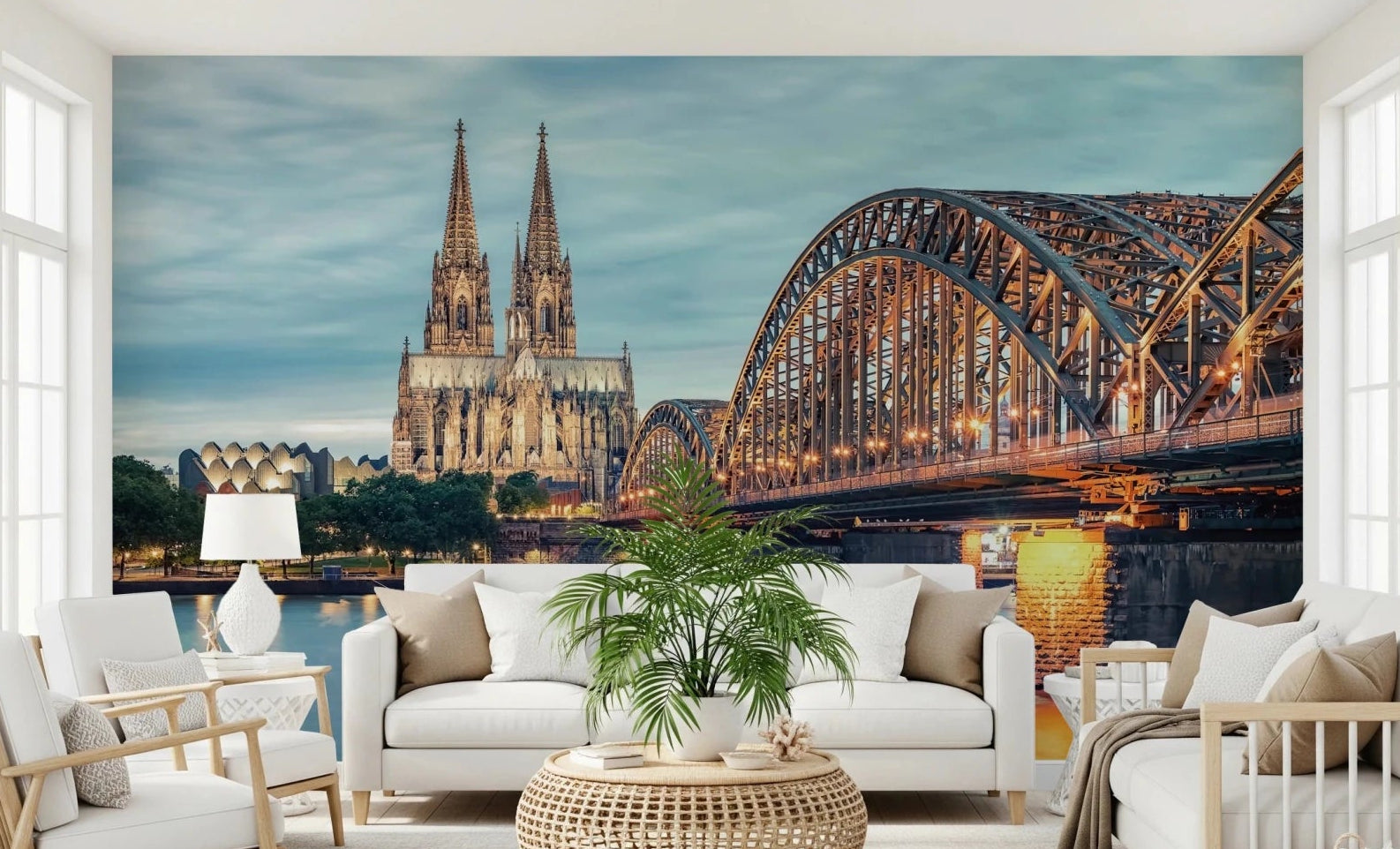 Cologne at Dusk wallpaper mural with the cathedral and Hohenzollern Bridge behind a white sofa and armchairs in a living room