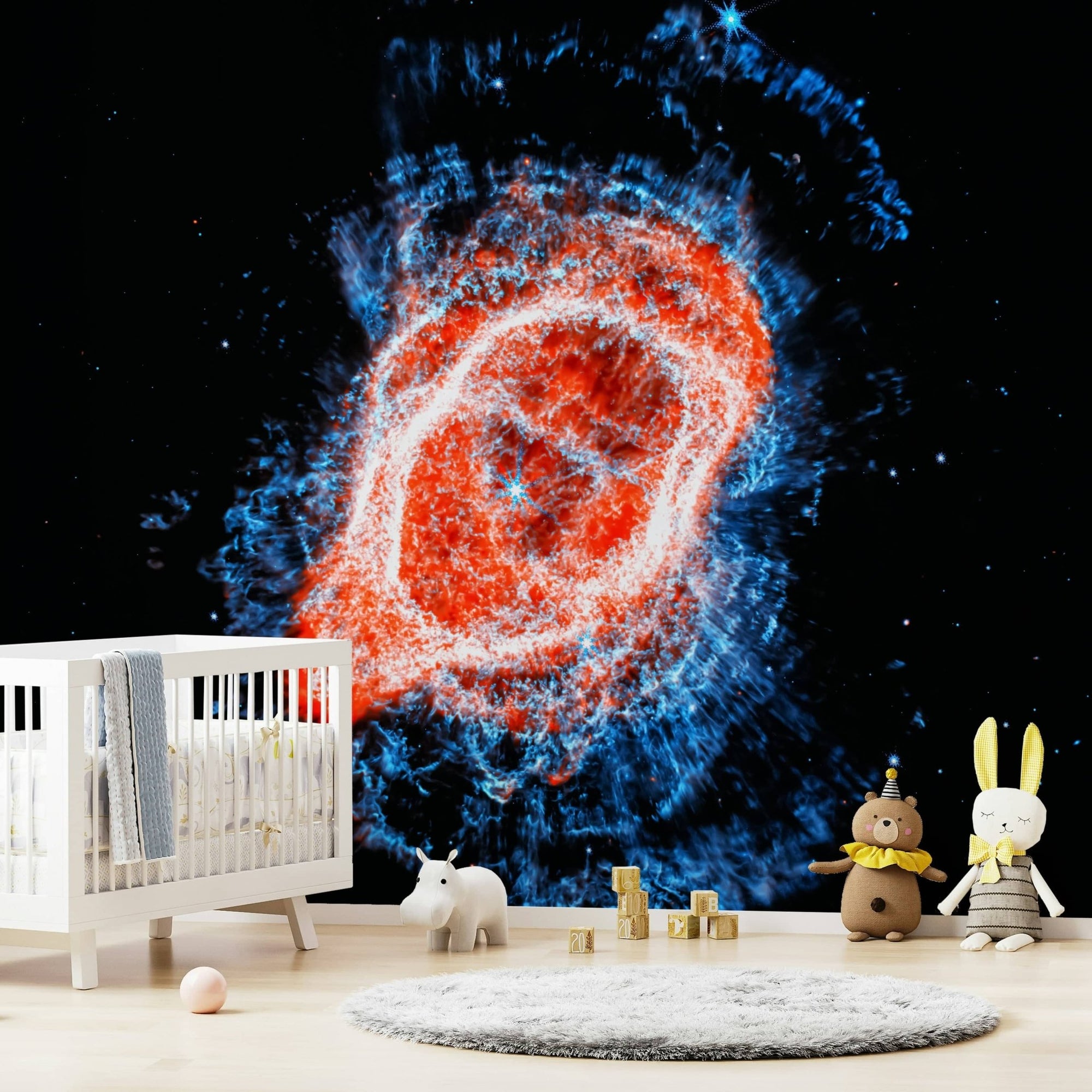 Cosmic Bloom wall mural of a red and blue nebula on black space behind a white crib and plush toys in a nursery