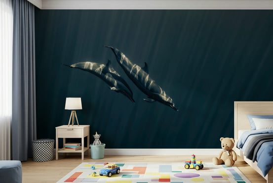Deep Blue Journey wallpaper mural of two dolphins gliding through deep blue ocean above a light wood bed and play rug in a kids room