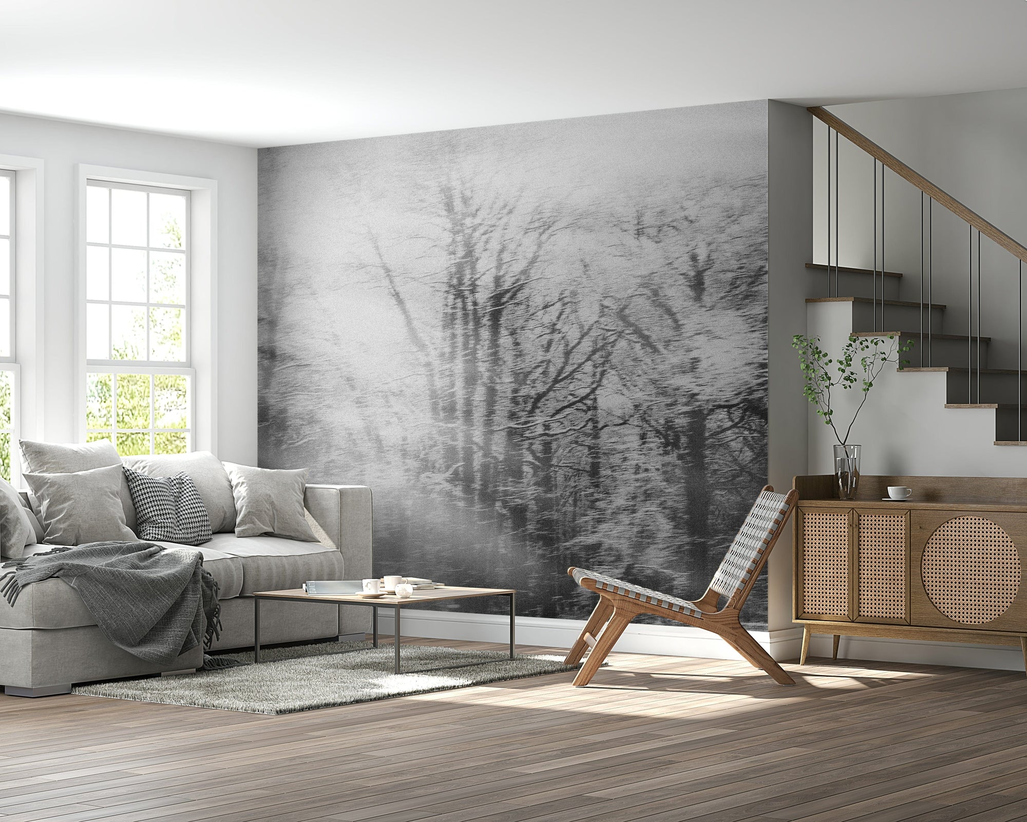 Ephemeral Grove wallpaper mural of a misty gray forest behind a gray sofa and cane sideboard near a staircase