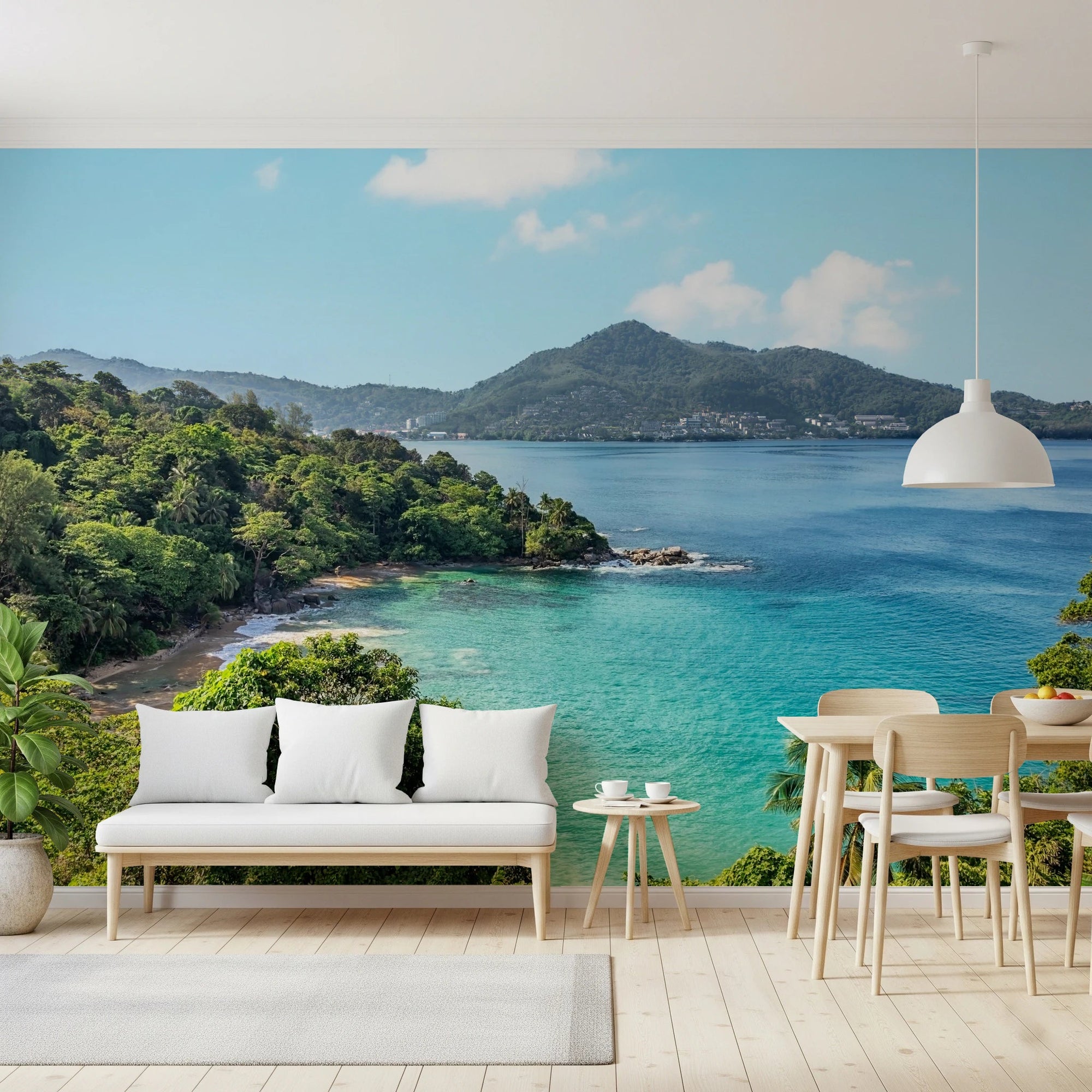 Emerald Shores wallpaper mural of a tropical jungle bay and turquoise sea behind a rattan daybed sofa on a terracotta-tiled living room