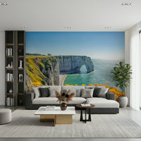 Etretat-inspired wall mural with yellow blossoms, green color foliage and calm sea wallpaper scene