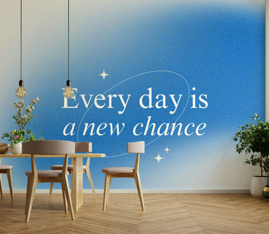 Every Day is a New Chance Blue Ombre wallpaper mural behind a wood dining table and chairs with pendant bulbs