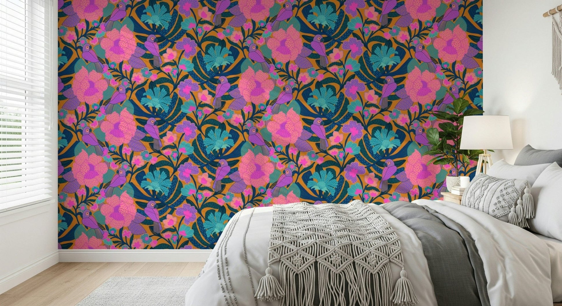Exotic Bloom wallpaper behind a white and grey bed with a macrame throw and bedside lamp