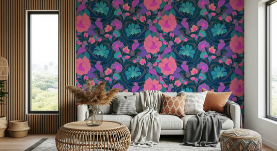 Exotic Garden wallpaper with pink and teal flowers and birds behind a grey sofa in a bright living room