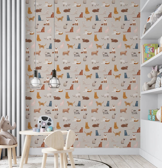 Feline Friends Forever wallpaper with illustrated cats on beige in a kids playroom with a wooden table and plush toys