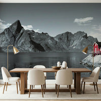 Coastal mountain mural with massive fjord cliffs and a vibrant red cabin at the water's edge.