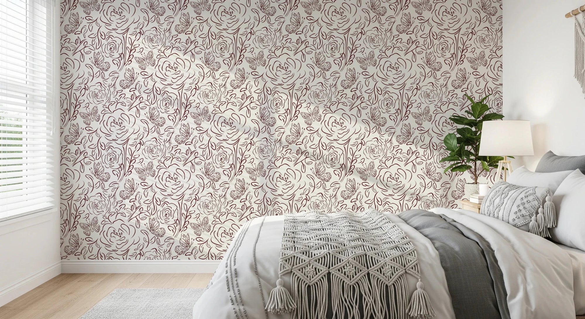 Floral Line Dance wallpaper in burgundy roses behind a grey bed with macrame throw and a leafy plant