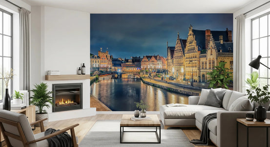 Ghent Lights wallpaper mural of an illuminated canal and medieval guild houses behind a white sectional sofa and fireplace in a living room