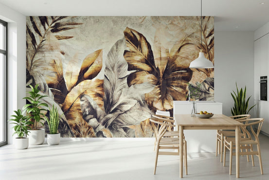 Golden Palm Abstract wallpaper mural of bold gold and brown banana leaves behind a light wood table with wishbone chairs