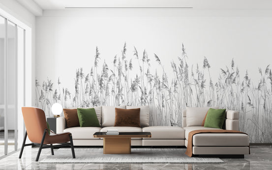 Gray Canebrake wallpaper mural of grayscale reed grasses behind a cream sofa and orange accent chair