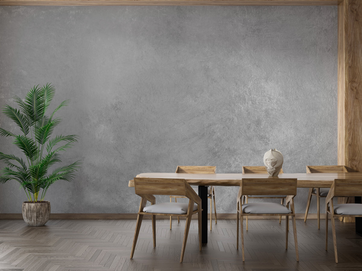 Gray Colored Textured wallpaper mural in soft gray plaster behind a wooden dining table and chairs with a potted palm
