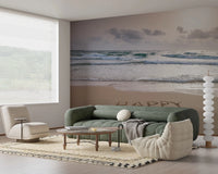 Happy Beach Vibes wallpaper mural of beach surf behind a sage green sofa and cream beanbag in a living room