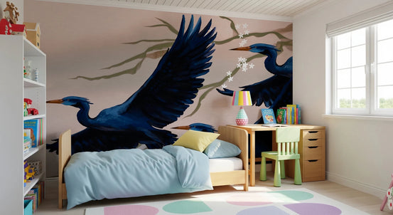 Heron's Bloom wallpaper mural of navy herons on blush behind a light blue bed and kids desk in a child's room