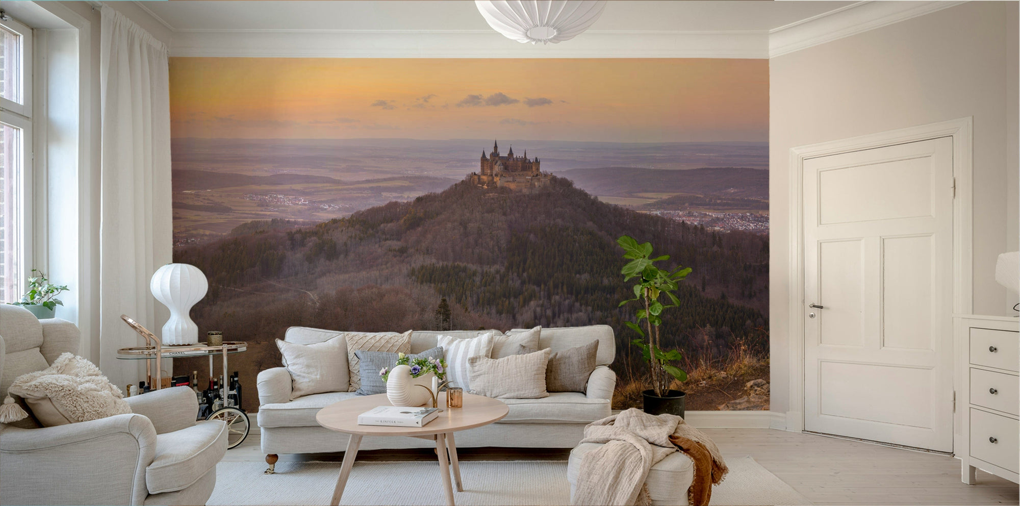 Medieval Majesty wallpaper mural of a hilltop castle at golden sunset behind a cream sofa in a bright living room